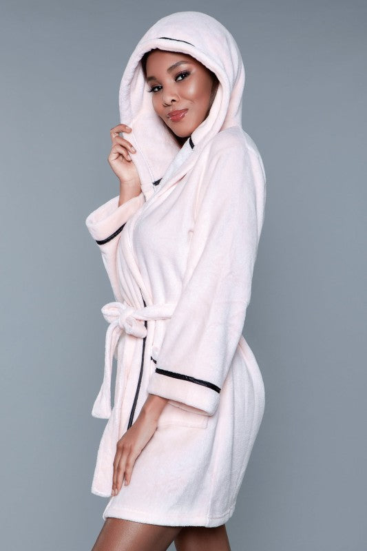 Woman wearing a white robe with a hood against a gray background