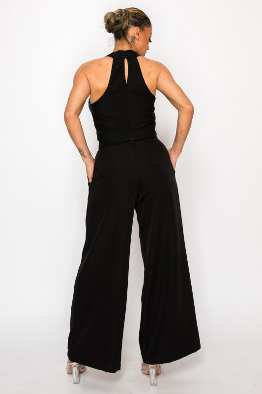 Woman wearing a black sleeveless top with black palazzo pants on a white background