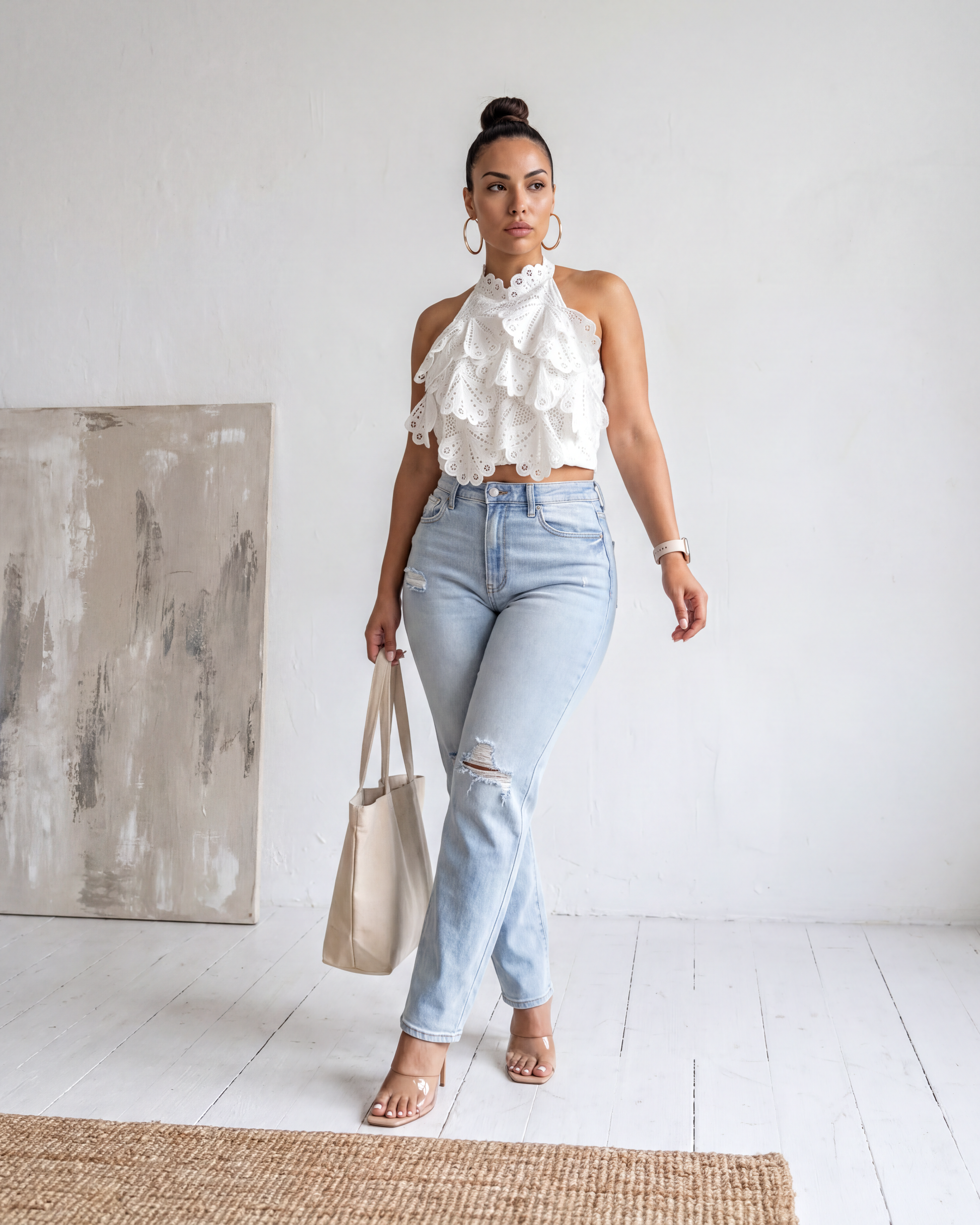 Front image full-body view of the Madison Distressed Straight Denim Jean in a light wash featuring distressed knees and a straight-leg fit, styled with a white ruffled top and a tote bag.