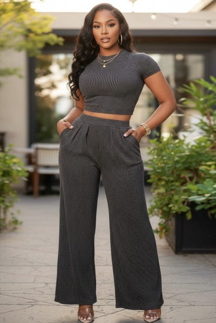 Front view of the female mode wearing the Olivia Pant Set in Charcoal featuring a fitted short-sleeve crop top and high-waisted wide-leg pants with pockets.