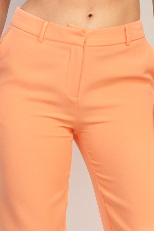 Close-up of a woman wearing peach pants on a neutral background