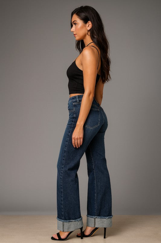 Woman wearing blue jeans and a black top against a gray background