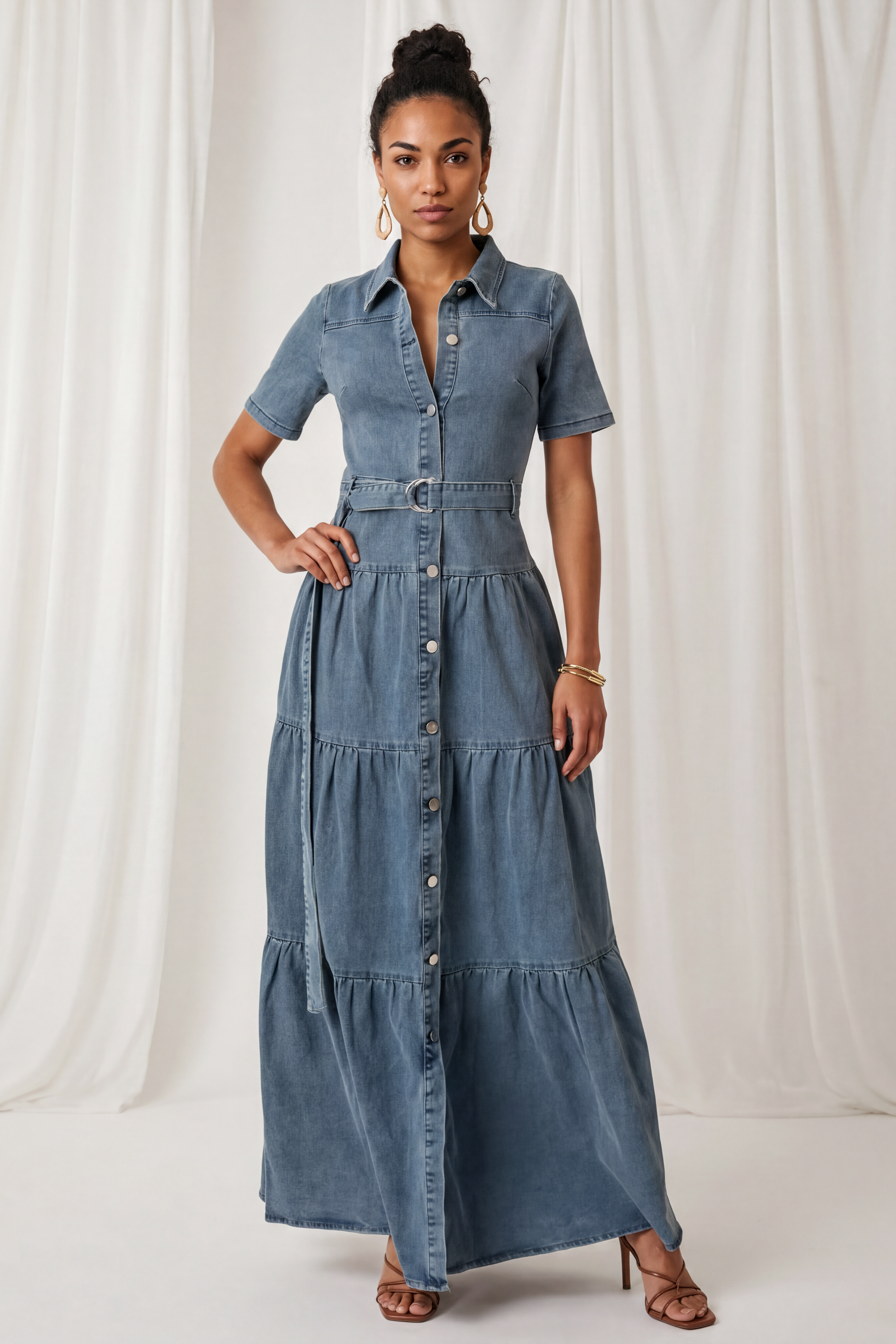 Front view of the Amora Denim Maxi Dress featuring short sleeves, a button-front closure, adjustable waist belt, and tiered maxi-length silhouette.