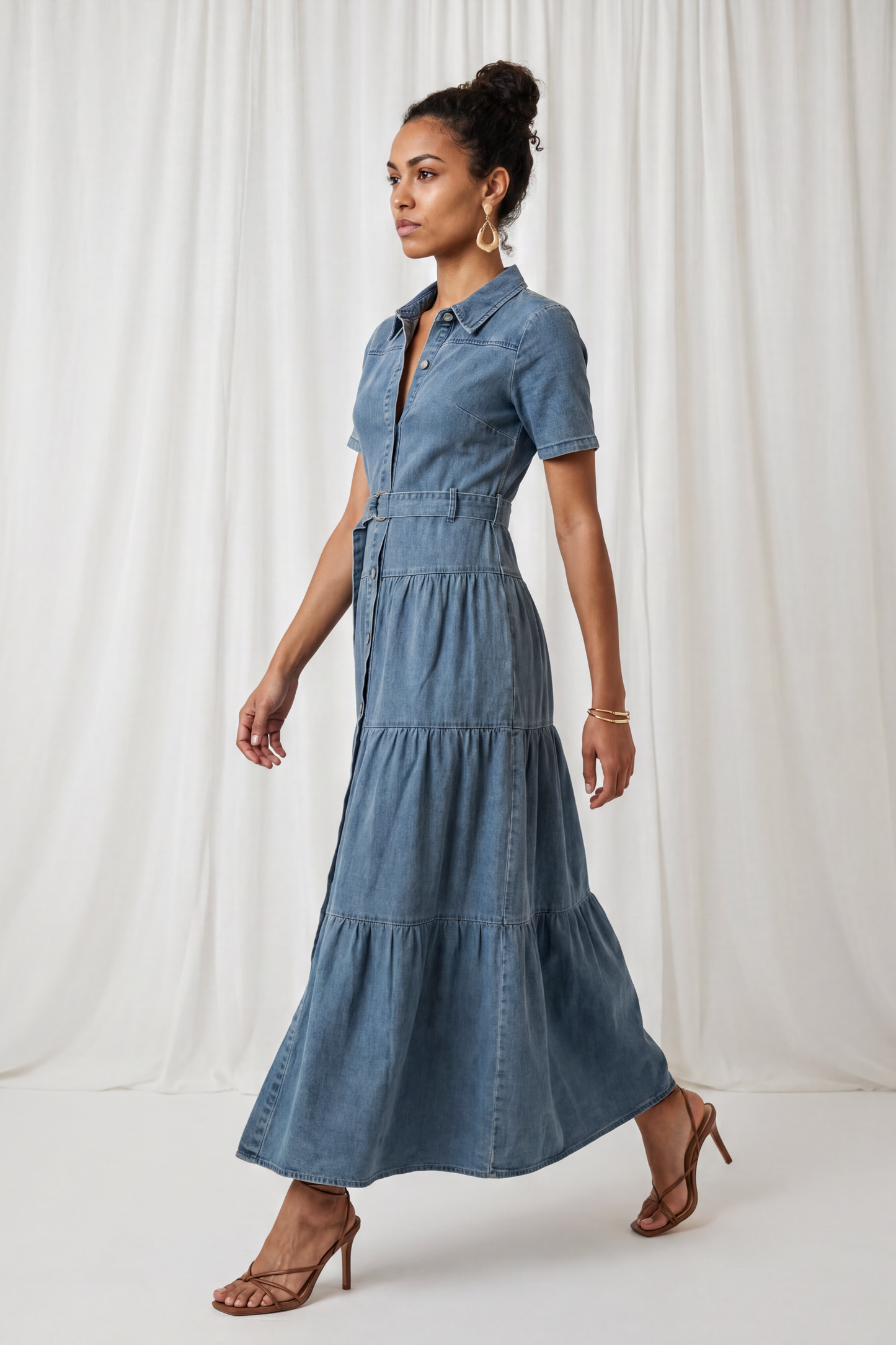 Side view of the Amora Denim Maxi Dress featuring short sleeves, a button-front design, adjustable waist belt, and tiered maxi-length skirt.