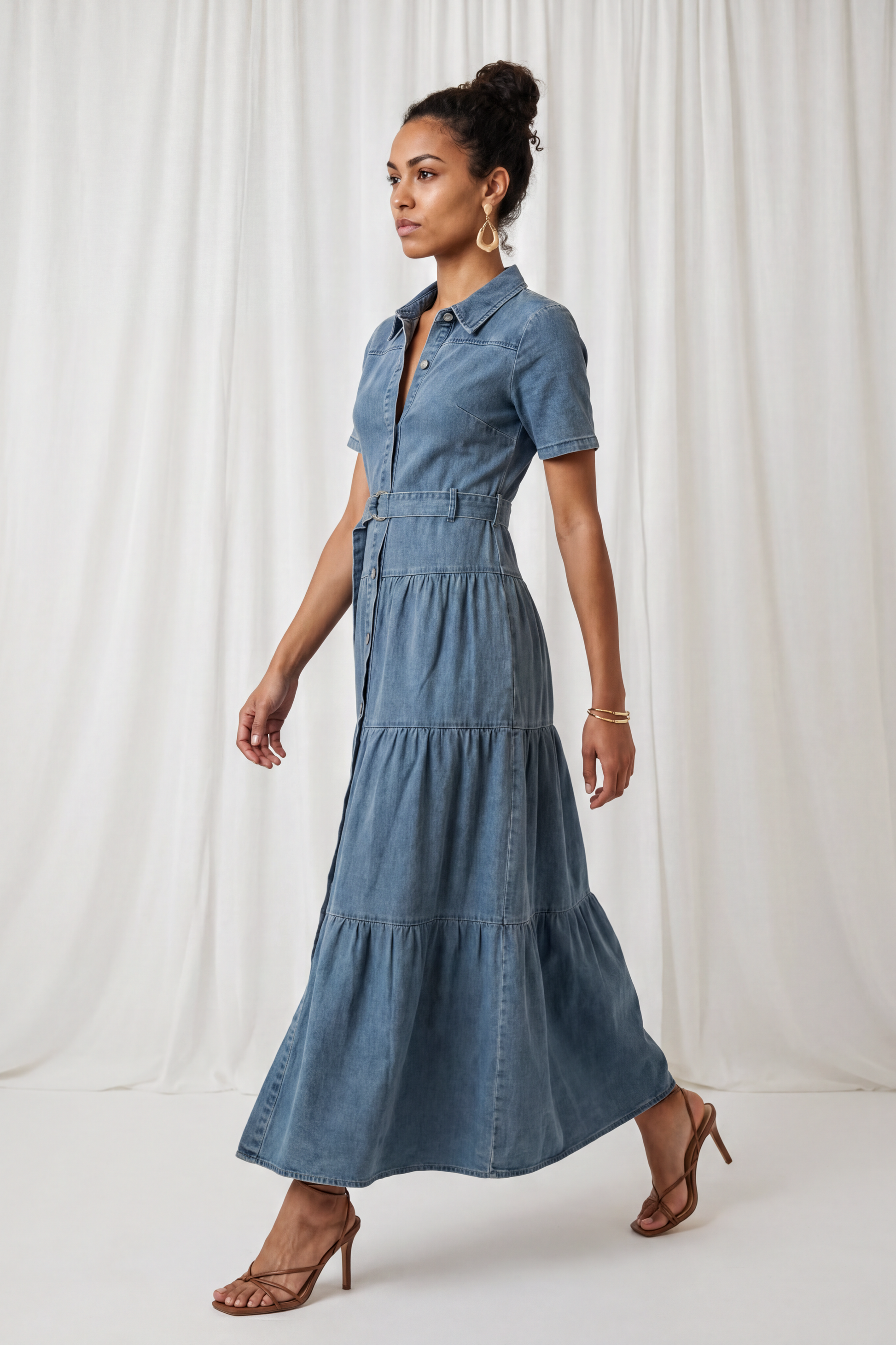 Side view of the Amora Denim Maxi Dress featuring short sleeves, a button-front design, adjustable waist belt, and tiered maxi-length skirt.