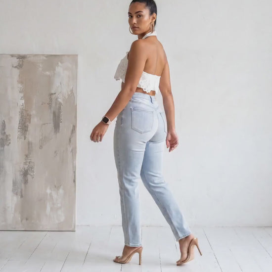 Angled back profile view of the Madison Distressed Straight Denim Jean in a light wash featuring distressed knees and a relaxed straight-leg fit.
